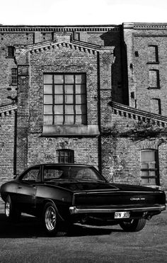 an old black and white photo of a car parked in front of a brick building