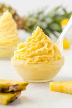 a bowl filled with pineapple whipped cream next to sliced pineapples