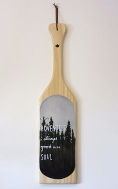 a wooden spoon hanging from the side of a wall with an image of trees on it