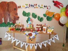 a birthday party with decorations and balloons on the wall, including a bear cake table