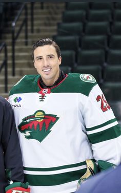 a man standing next to another man in a hockey uniform