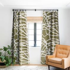 a chair sitting in front of a window next to a potted plant on top of a rug