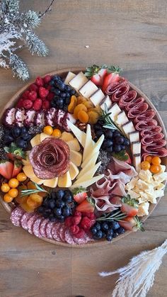 a platter filled with meats, cheeses and fruit on top of a wooden table