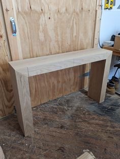 a wooden bench sitting on top of a hard wood floor next to plywood boards