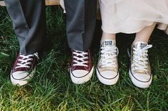 two people standing next to each other on top of green grass with white converse shoes