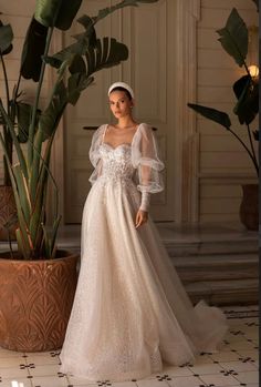 a woman in a wedding dress standing next to a potted plant