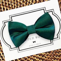 a green bow tie sitting on top of a white card next to a woven basket