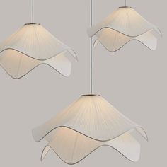 three white lamps hanging from the ceiling in an artistic manner, one is shaped like a bird