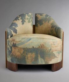 an upholstered chair with floral fabric and wooden legs, on a gray background