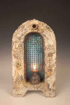 a candle is lit inside of a stone structure with holes in the front and sides