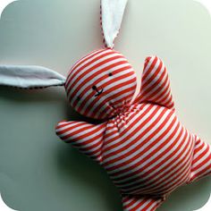 a red and white striped stuffed animal laying on top of a round plate with a spoon