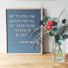 a vase filled with flowers sitting next to a framed sign that says not to spoil the ending for you but everything is going to be okay