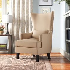 a beige chair sitting on top of a hard wood floor next to a book shelf