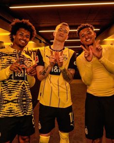 three soccer players are posing for a photo in the locker room with their hands together