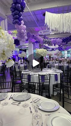 tables and chairs are set up for an event with purple balloons hanging from the ceiling