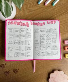 an open book sitting on top of a wooden table next to erasers and pencils