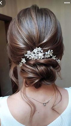 a woman wearing a hair comb with flowers on it's head and her hair pulled back into a low bun