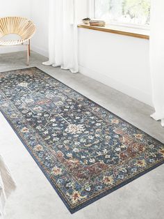 a large blue rug in a room with white curtains and a chair next to it