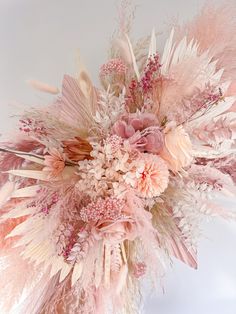 an arrangement of pink flowers and feathers in a vase