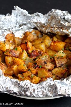 potatoes in foil on a plate with parsley sprinkled around them, ready to be eaten