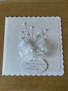 a white card with a bow and ribbon on it's side, sitting on top of a wooden table