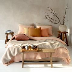 a bed with pillows and blankets on top of it next to a wooden coffee table