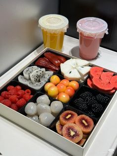 an assortment of fruits and ice creams on a tray with two cups in the background