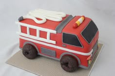 a cake shaped like a firetruck sitting on top of a cloth covered table