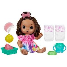 a doll with brown hair sitting in front of some toys and accessories on a white background