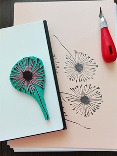 a notebook with a dandelion design on it next to a pen and paper clip