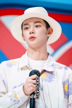 the boy is wearing a white hat and holding a microphone