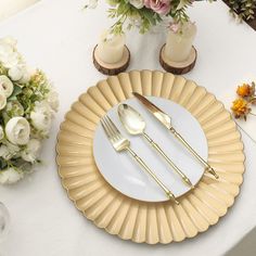 a white table topped with plates and silverware next to vases filled with flowers