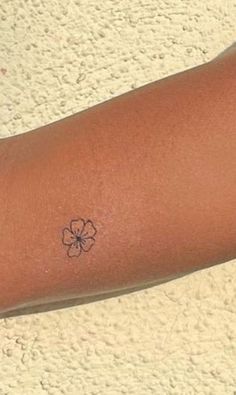 a person's arm with a small flower tattoo on the left side of their arm