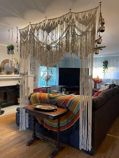 a living room with a couch, table and macrame hanging from the ceiling