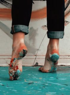 the legs and feet of a person standing on a blue floor with paint all over them