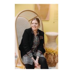 a woman sitting in a chair next to a vase on the floor and smiling at the camera