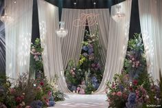 a wedding stage decorated with flowers and chandelier hanging from it's ceiling