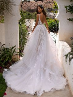 a woman in a white wedding dress standing on a stone walkway with her back to the camera