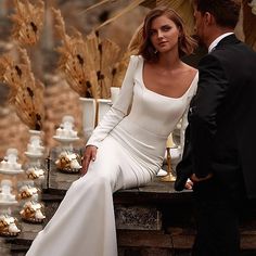 a man and woman in formal wear sitting next to each other on a stone wall