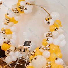 an arch made out of balloons in the shape of a circle with gold and white balls