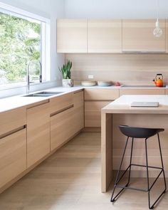 a kitchen with wooden cabinets and stools next to a counter top on a hard wood floor