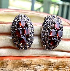 "Stunning Sterling Marcasite & garnet clip on earrings. A 1\" by 5/8\" domed (3/8\") Marcasite oval. Each earrings have 4 ovals garnet (not tested). Comfortable clip on with the mark on both earring \"925\" for silver sterling. Both earrings weight is 0.54oz/15.39g In excellent condition, expected minor signs of wear. Comes in a gift box." Oval Garnet Gemstone Earrings, Silver Oval Clip-on Earrings, Silver Oval Clip-on Earrings For Formal Events, Silver Oval Clip-on Earrings For Formal Occasions, Oval Gemstone Clip-on Earrings For Gifts, Antique Oval Clip-on Jewelry, Oval Sterling Silver Clip-on Earrings, Vintage Jewelry Earrings, Gemstones Jewelry