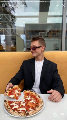 a man sitting at a table with a pizza in front of him