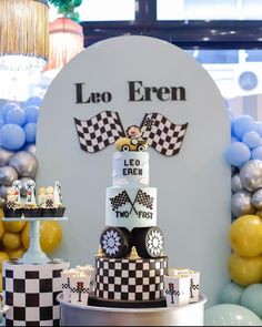 a birthday cake decorated with race cars and balloons in front of a sign that says lao eren