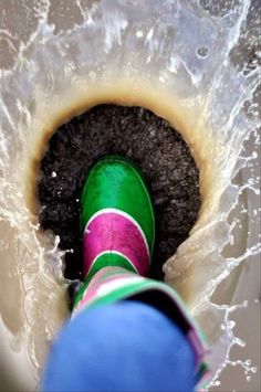 a person standing in a sink filled with water and dirt next to a green bottle