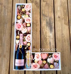 a bottle of champagne and some flowers in a box on a wooden table next to it