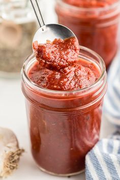 a spoon full of sauce sitting on top of a jar