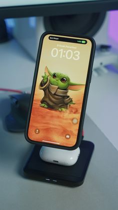 an iphone with the baby yoda character on it sitting in front of a computer monitor