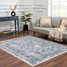 a living room area with a couch, chair and rug on the hardwood flooring