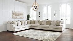 a living room with a large sectional couch and rug on the floor in front of two windows